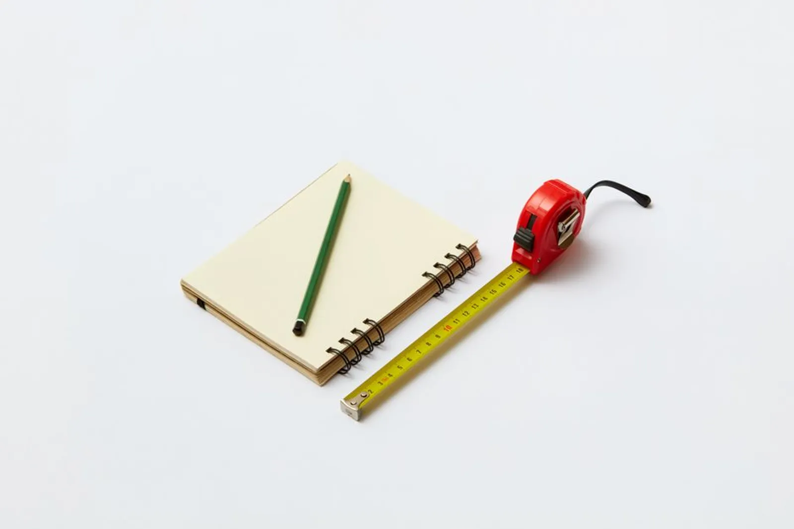 Carnet de chantier ouvert sur un établi, mètre ruban et crayon posés à côté